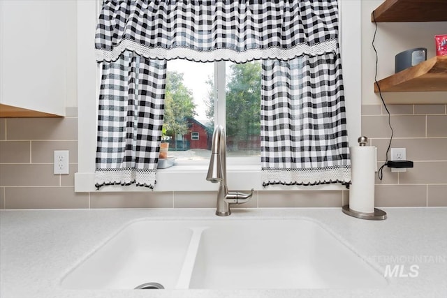 interior details featuring light countertops, a sink, and tasteful backsplash