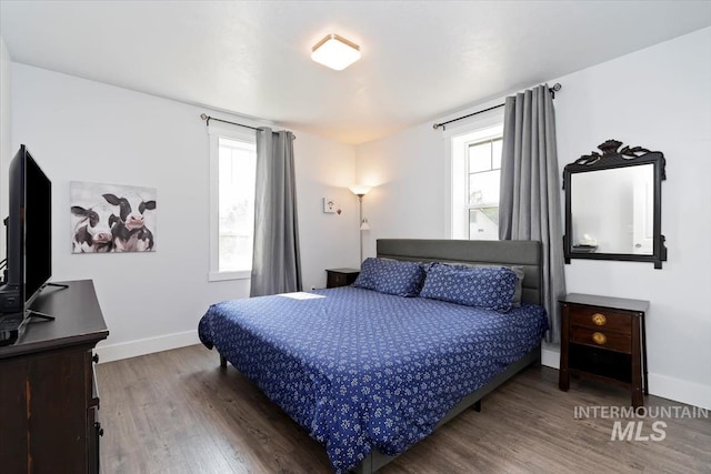 bedroom featuring baseboards, multiple windows, and wood finished floors