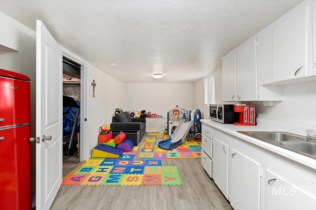rec room featuring a sink, a textured ceiling, and light wood-type flooring