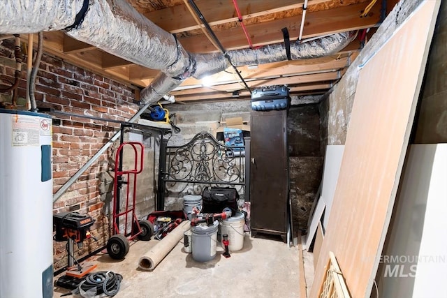 unfinished below grade area featuring water heater and brick wall