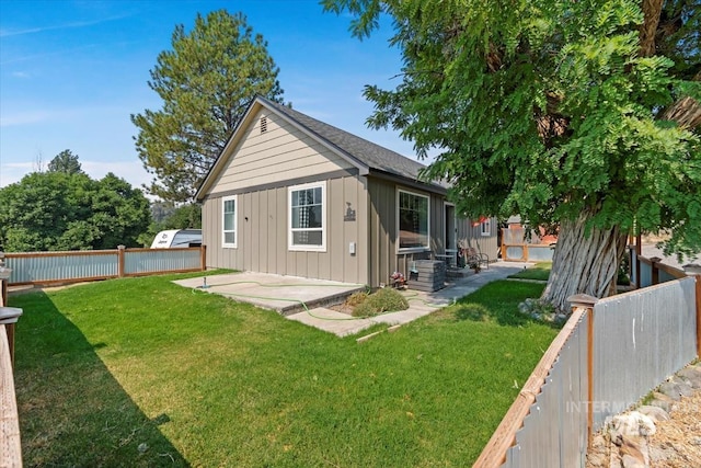 rear view of house featuring a lawn, a fenced backyard, board and batten siding, and a patio