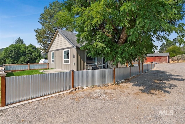 view of front of property with a fenced front yard, board and batten siding, and roof with shingles