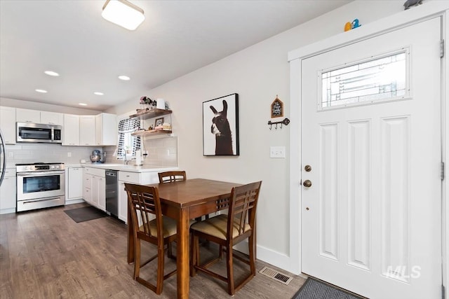 dining room with dark wood-style flooring, visible vents, and a wealth of natural light