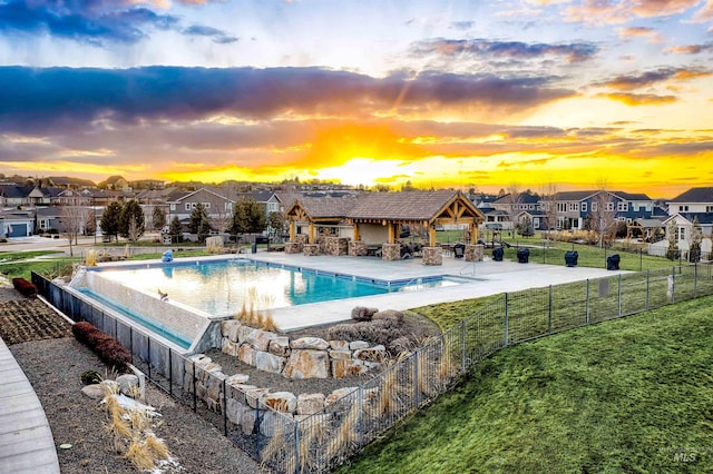 pool at dusk featuring a gazebo, a yard, and exterior kitchen