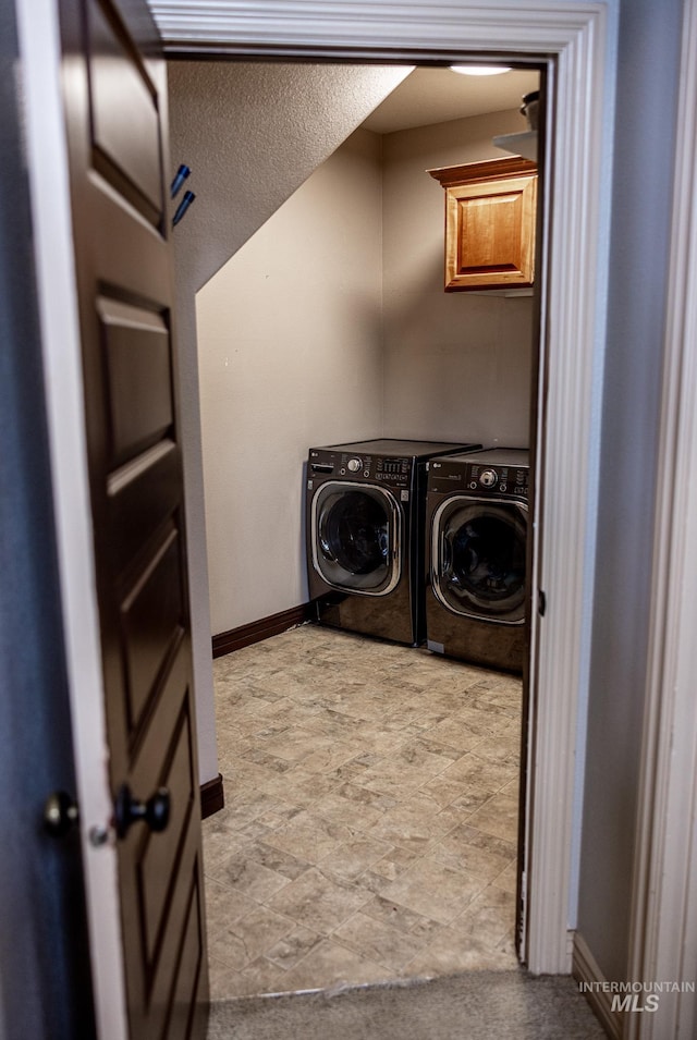 clothes washing area with cabinets and separate washer and dryer