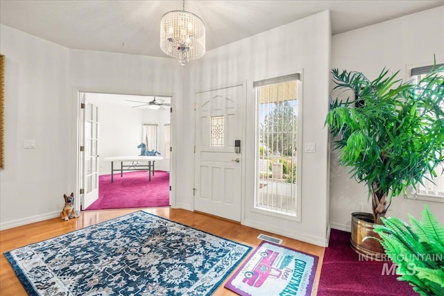 foyer entrance featuring an inviting chandelier, baseboards, wood finished floors, and visible vents