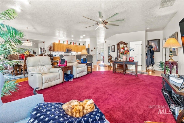 carpeted living area featuring visible vents, a textured ceiling, and ceiling fan