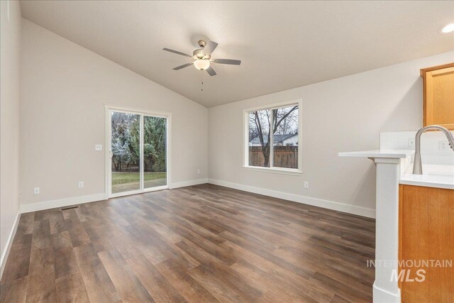 unfurnished living room with baseboards, lofted ceiling, ceiling fan, dark wood-type flooring, and a sink