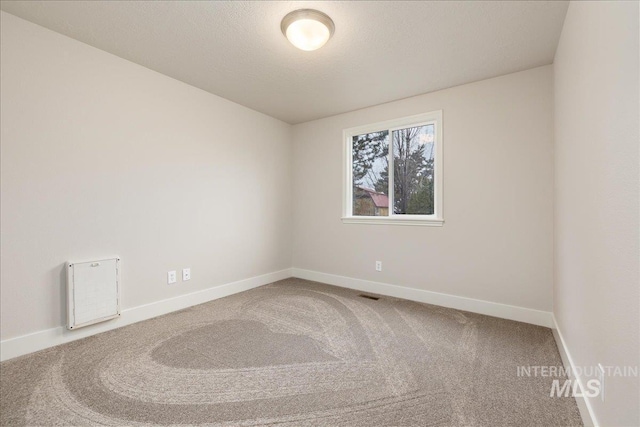 carpeted spare room with visible vents, a textured ceiling, and baseboards