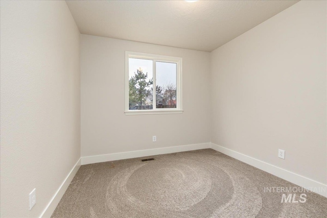 empty room with carpet floors, visible vents, and baseboards