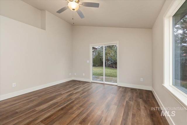 empty room featuring lofted ceiling, dark wood finished floors, a ceiling fan, and baseboards