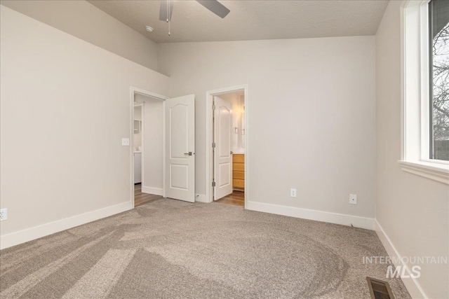 unfurnished bedroom with carpet, visible vents, vaulted ceiling, and baseboards