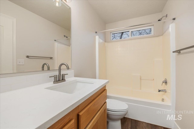 bathroom featuring a textured ceiling, toilet, wood finished floors, vanity, and shower / washtub combination