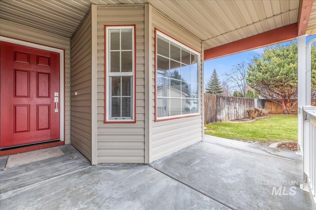 entrance to property featuring fence and a lawn