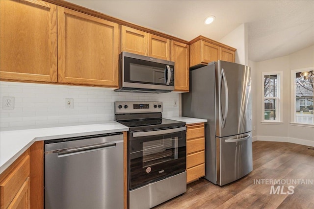 kitchen featuring lofted ceiling, appliances with stainless steel finishes, light countertops, and backsplash