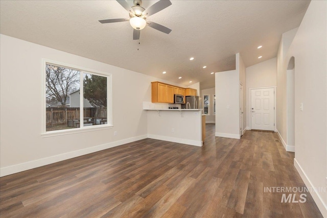 unfurnished living room featuring lofted ceiling, dark wood finished floors, a textured ceiling, and baseboards