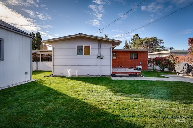 back of property with a lawn and a deck