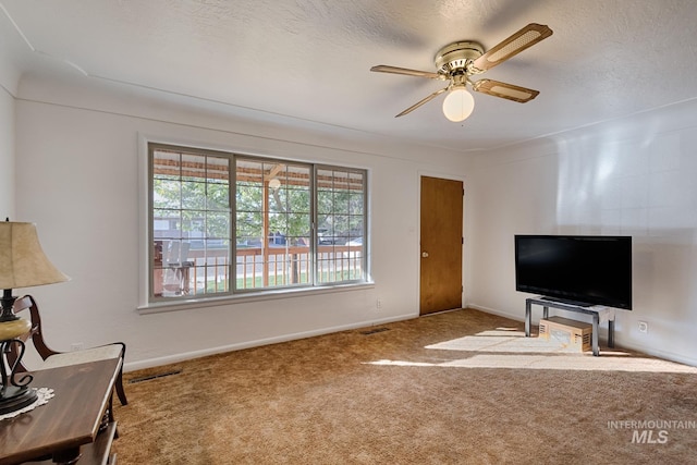 living room with ceiling fan, carpet, and a textured ceiling