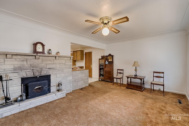 living area featuring carpet floors, a fireplace, and ceiling fan