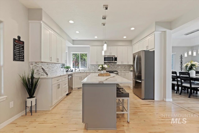 5915 N Lilybrook Pl, Boise, ID 83713 - kitchen featuring stainless steel appliances, light wood finished floors, a kitchen bar, decorative backsplash, and recessed lighting