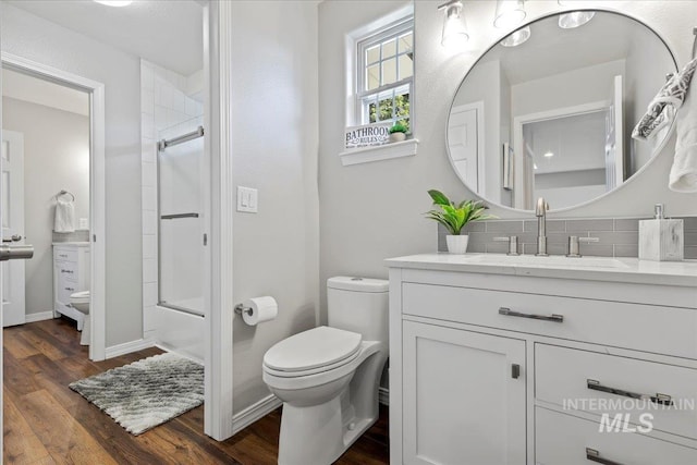 5915 N Lilybrook Pl, Boise, ID 83713 - bathroom with toilet, vanity, decorative backsplash, wood finished floors, and shower / bath combination with glass door