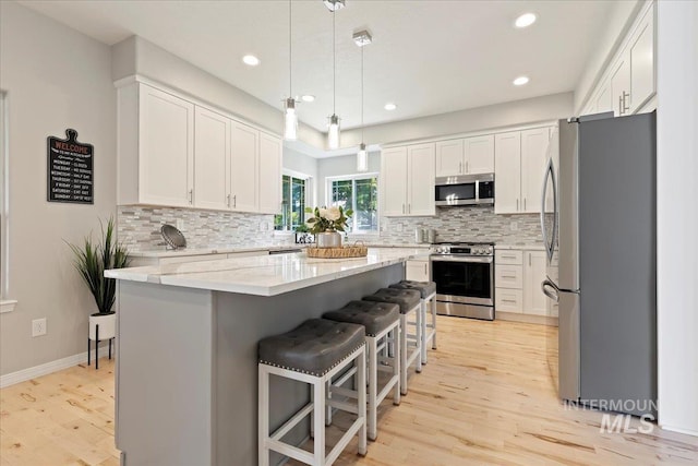 5915 N Lilybrook Pl, Boise, ID 83713 - kitchen with appliances with stainless steel finishes, light wood-style flooring, tasteful backsplash, a kitchen bar, and recessed lighting