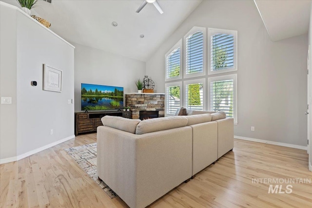 5915 N Lilybrook Pl, Boise, ID 83713 - living area featuring high vaulted ceiling, a ceiling fan, light wood-style floors, a stone fireplace, and baseboards