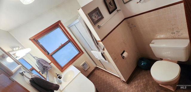 bathroom featuring sink, tile patterned flooring, toilet, and tile walls