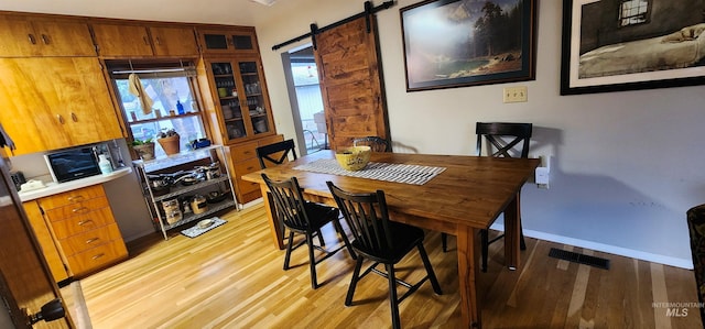 dining room with a barn door and light hardwood / wood-style floors