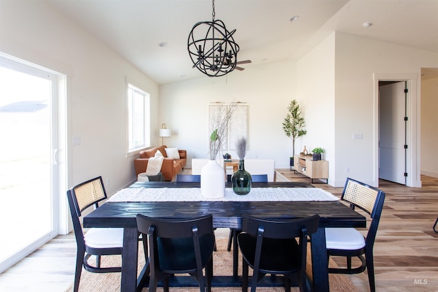 dining room with baseboards, lofted ceiling, a chandelier, and light wood-style flooring