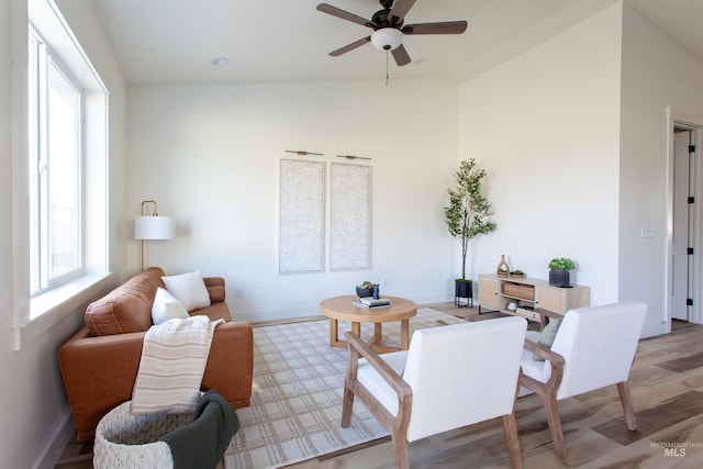 living room featuring vaulted ceiling, a ceiling fan, light wood-type flooring, and baseboards