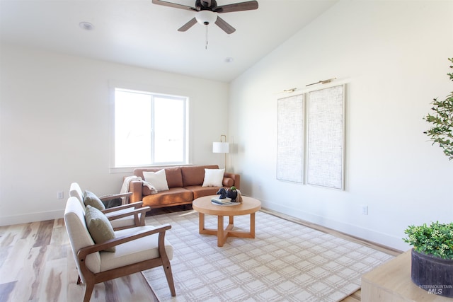 living area featuring lofted ceiling, baseboards, light wood finished floors, and ceiling fan