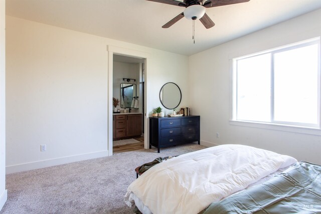 bedroom with a ceiling fan, baseboards, light carpet, and ensuite bathroom