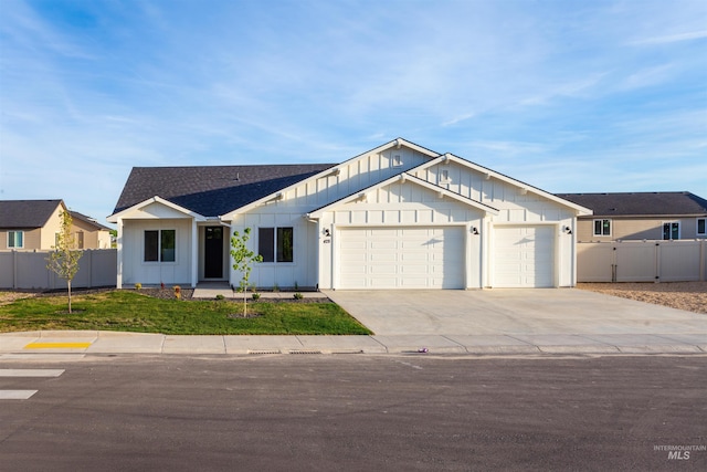 modern farmhouse featuring fence, driveway, board and batten siding, and a garage