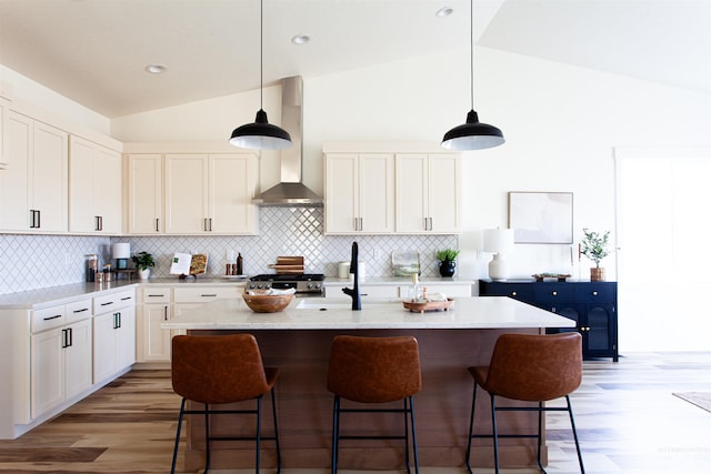 kitchen with stove, vaulted ceiling, wall chimney exhaust hood, and light wood-type flooring