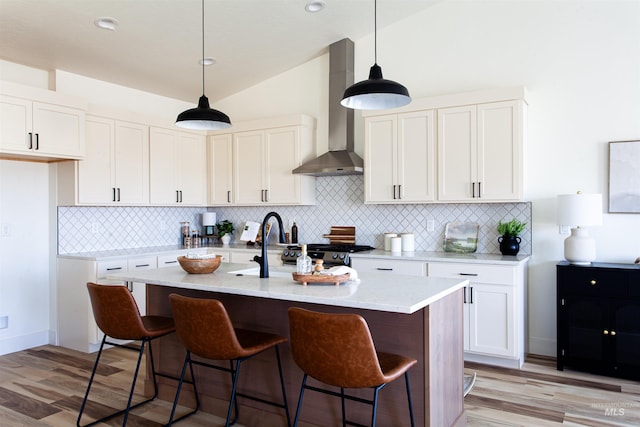 kitchen with wall chimney range hood, backsplash, and light wood-type flooring