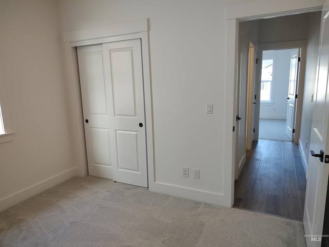 unfurnished bedroom with light colored carpet and a closet