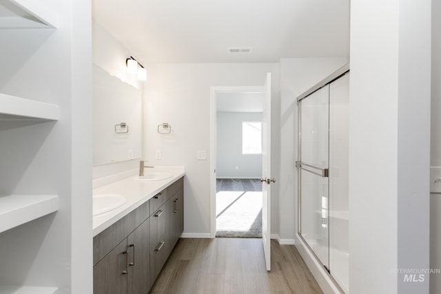 bathroom with vanity, a shower with shower door, and wood-type flooring