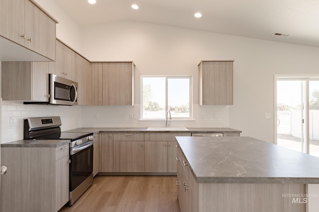 kitchen featuring appliances with stainless steel finishes, vaulted ceiling, and light brown cabinets