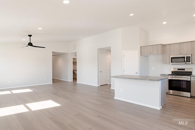 kitchen with ceiling fan, stainless steel appliances, light hardwood / wood-style floors, a kitchen island, and light brown cabinetry