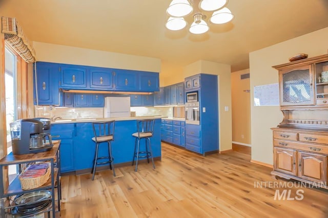 kitchen featuring a breakfast bar, blue cabinetry, tasteful backsplash, appliances with stainless steel finishes, and light wood finished floors