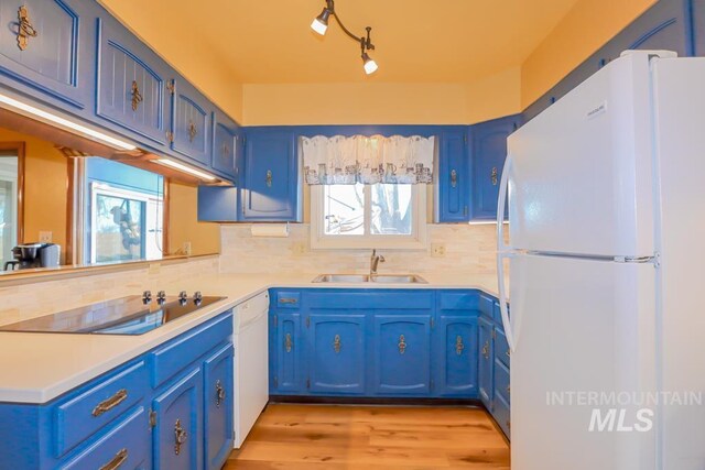 kitchen featuring blue cabinets, black electric stovetop, a sink, and freestanding refrigerator