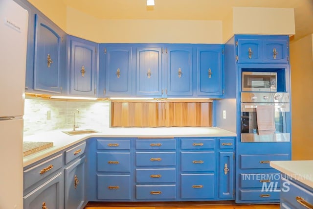 kitchen with blue cabinetry, stainless steel appliances, and a sink