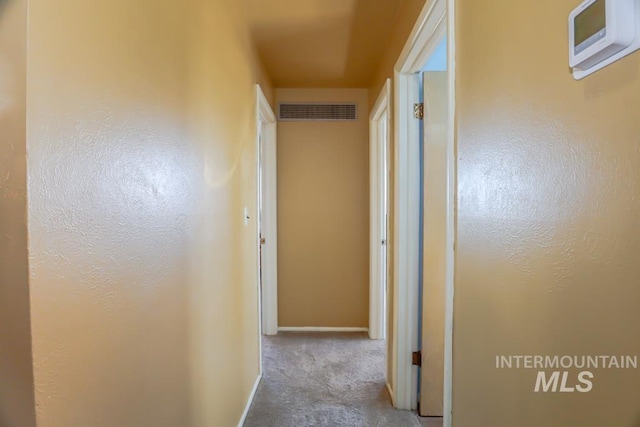 hall with visible vents, baseboards, and carpet