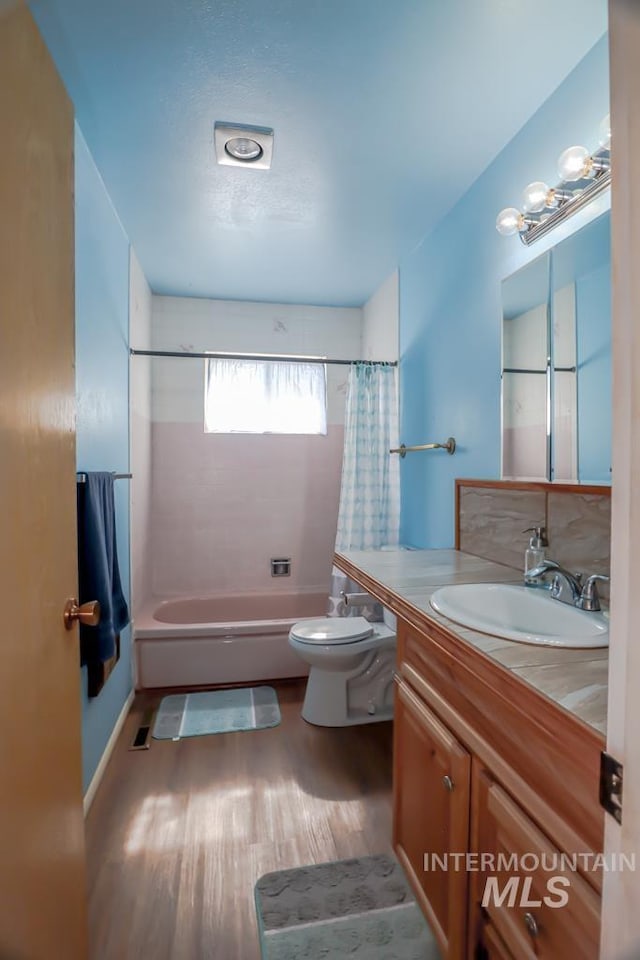 bathroom with shower / bathtub combination with curtain, toilet, wood finished floors, and vanity