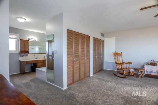 carpeted bedroom featuring visible vents, two closets, and ensuite bathroom