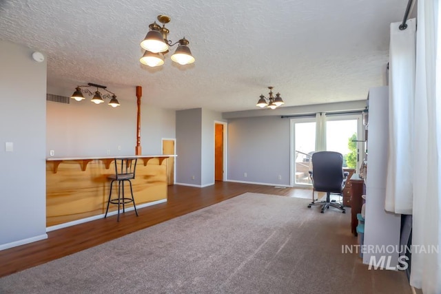 office area with visible vents, a notable chandelier, a textured ceiling, wood finished floors, and baseboards