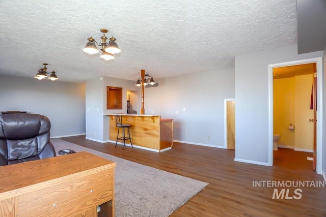 office space with a textured ceiling, wood finished floors, baseboards, and a chandelier