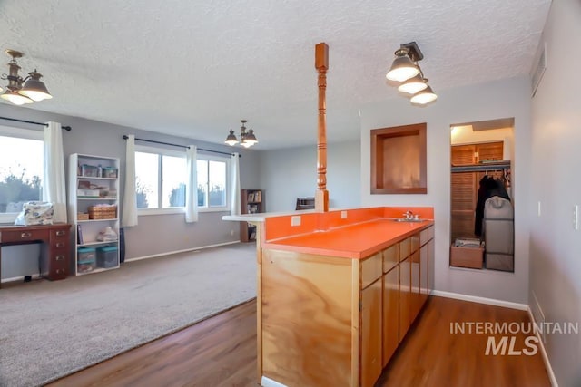 kitchen with dark wood finished floors, open floor plan, a peninsula, and a textured ceiling