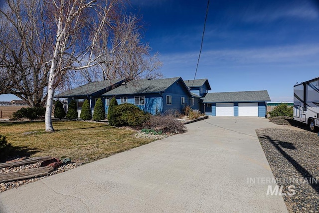 ranch-style house featuring a garage, an outbuilding, concrete driveway, and a front yard